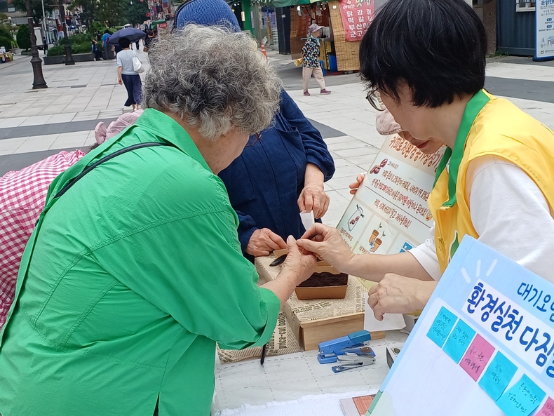 4일 화정동 로데오거리에서 신천지자원봉사단 고양지부 회원이 지나가는 시민들에게 커피 찌꺼기를 활용한 공기청정기를 소개하며, 제작 방법을 설명하고 있다.