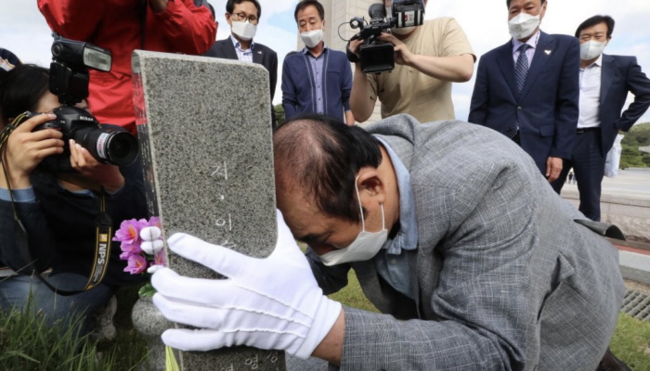 광주 북구 국립5·18민주묘지에서 21일 오후 신순용 전 육군 소령이 옛 광주교도소 관련 열사의 묘비를 붙잡고 사죄하고 있다. 연합뉴스